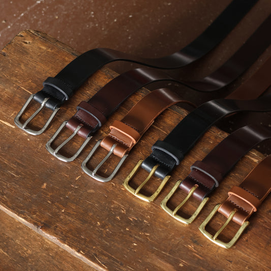 Set of leather belts with different buckles on a wooden surface