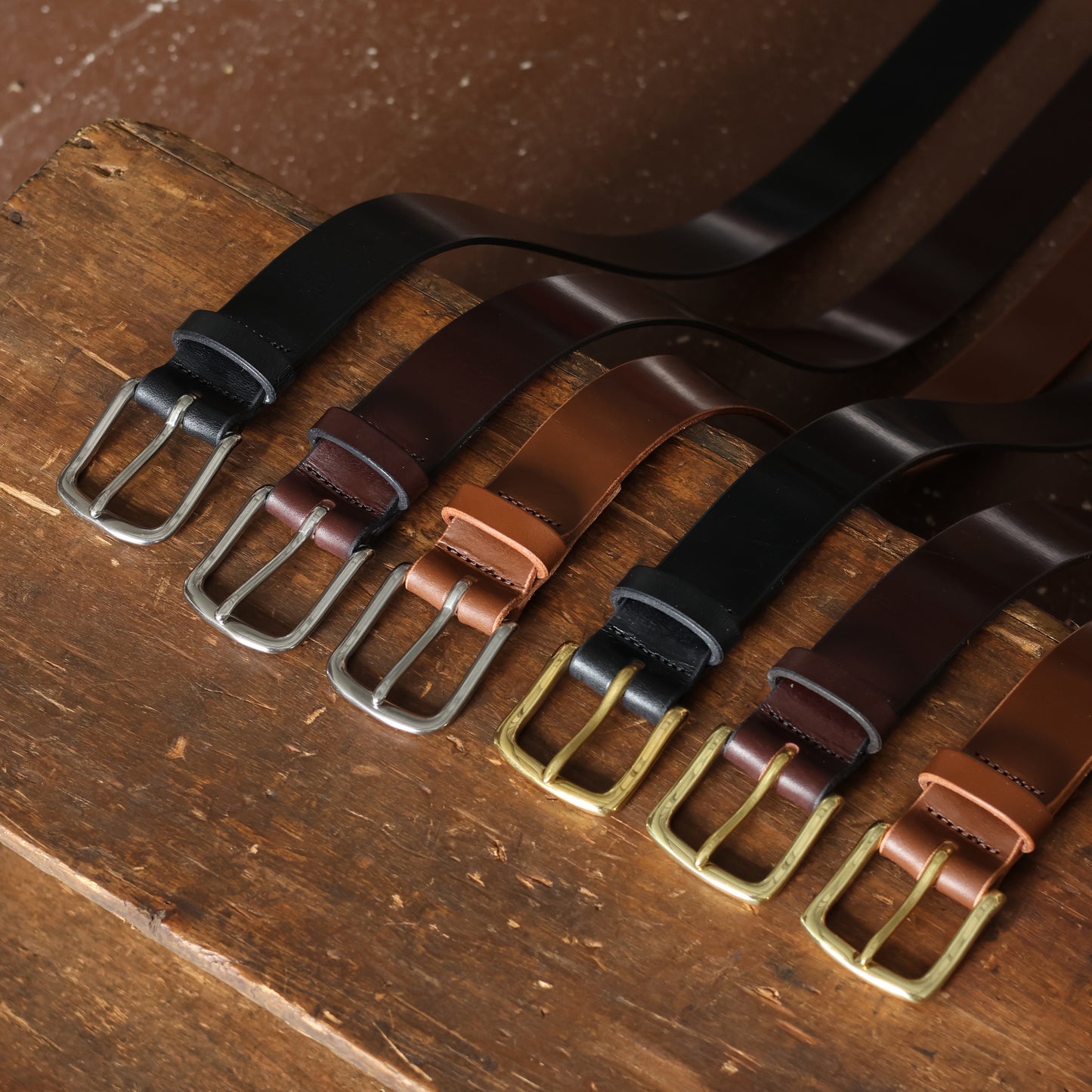 Set of leather belts with different buckles on a wooden surface