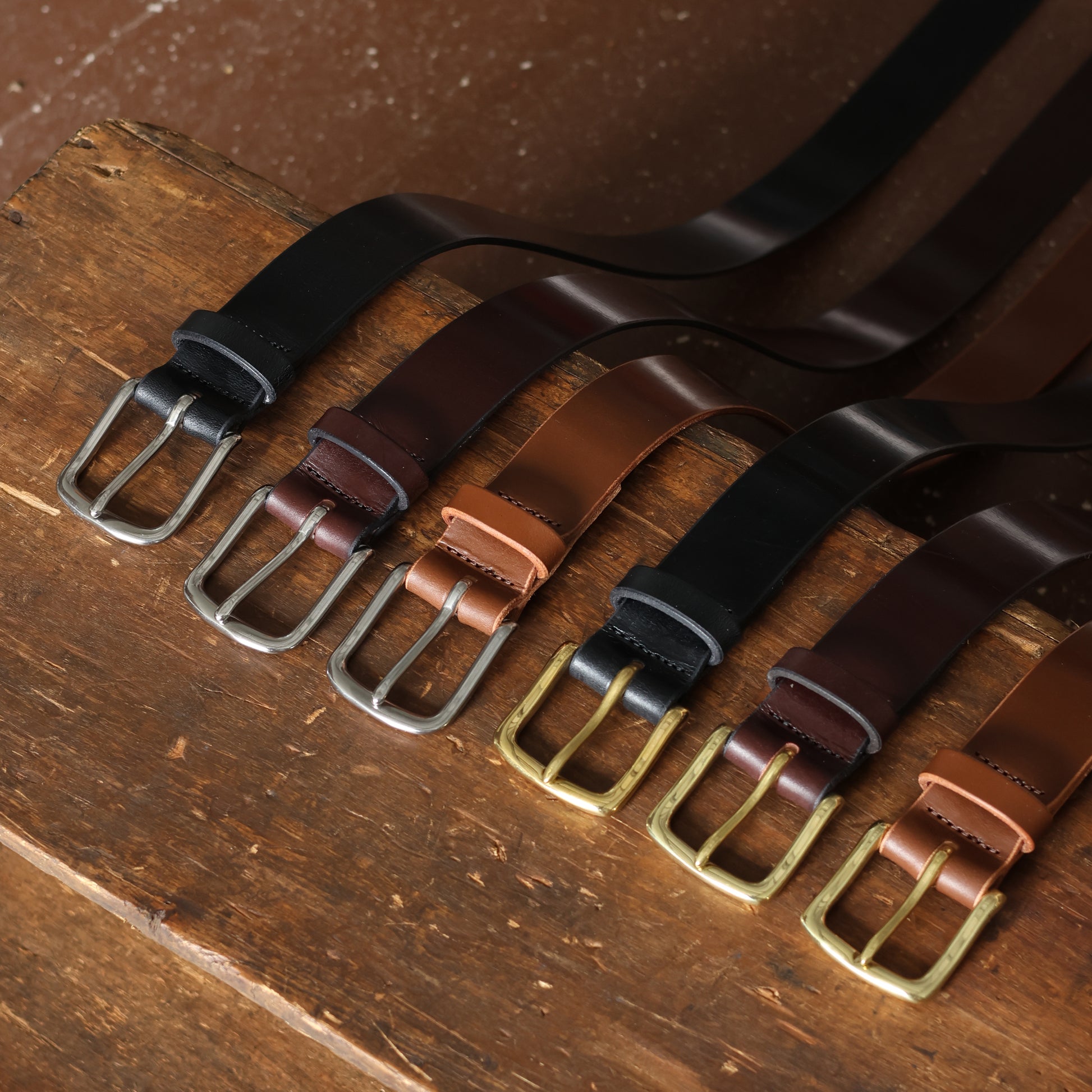 Set of leather belts with different buckles on a wooden surface