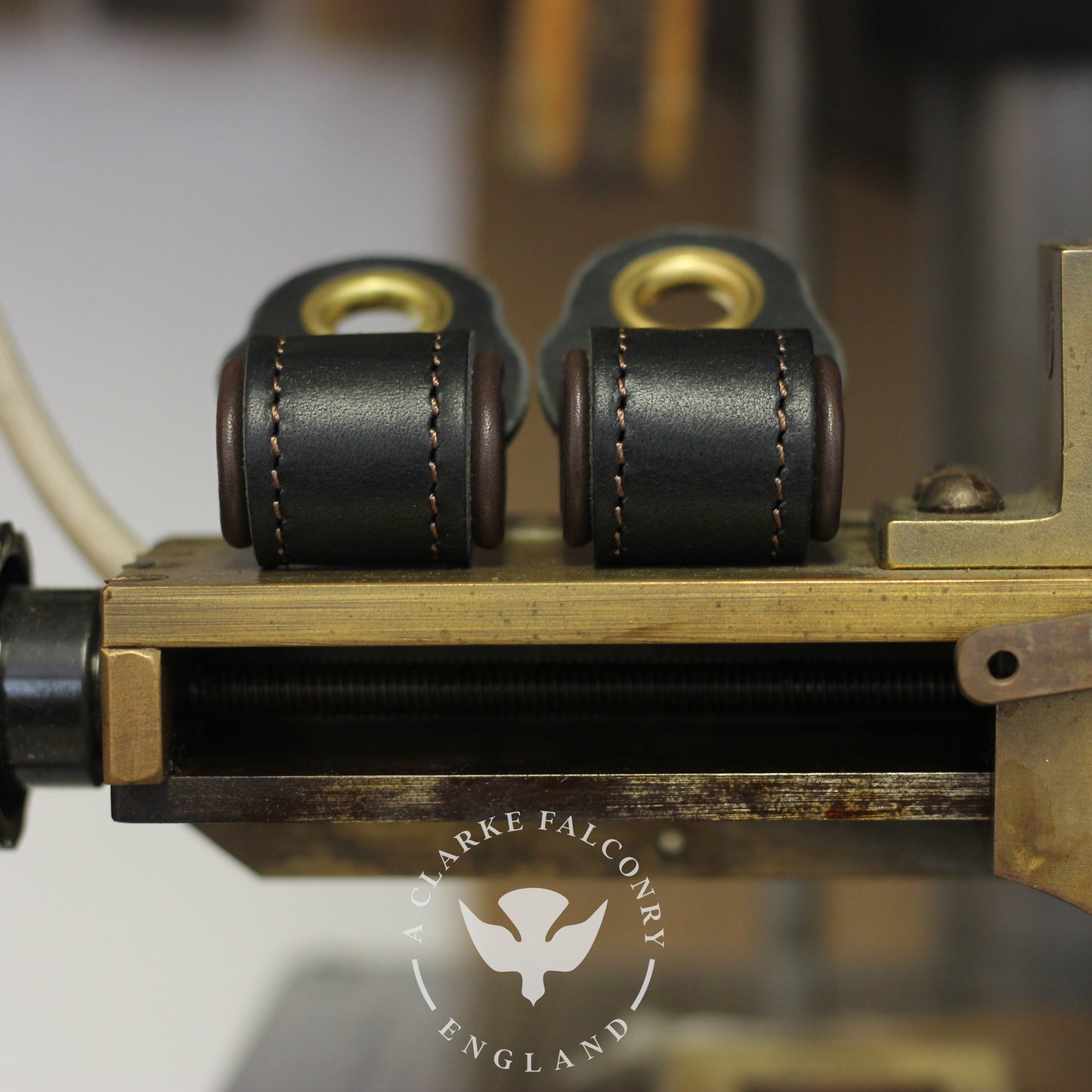 Two black and brown lined falconry anklets fitted on a device, with the brand 'A Clarke Falconry' visible.