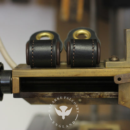Two black and brown lined falconry anklets fitted on a device, with the brand 'A Clarke Falconry' visible.